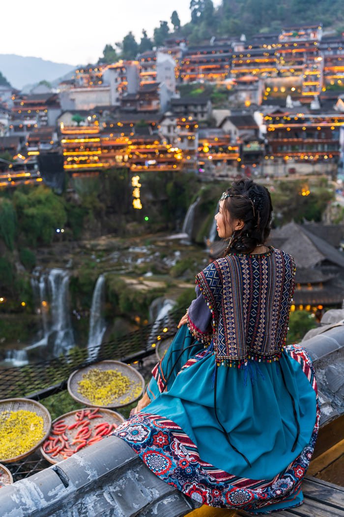 Mujer de espalda viendo la ciudadade Lijiang iluminada